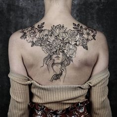 the back of a woman's shoulder with flowers on her neck and chest tattoo