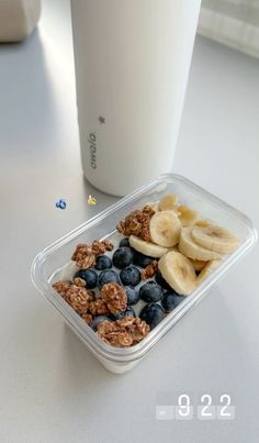 a plastic container filled with granola and blueberries next to a glass of milk