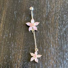 a pink flower dangling from a chain on top of a wooden table next to a pair of scissors