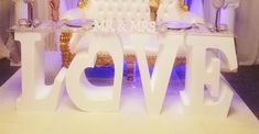 a large white cake sitting on top of a table with the word love spelled out in front of it