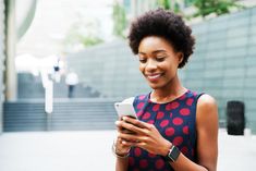 a woman smiles while looking at her cell phone