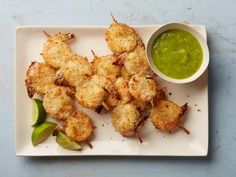 chicken skewers with green dipping sauce on a white plate