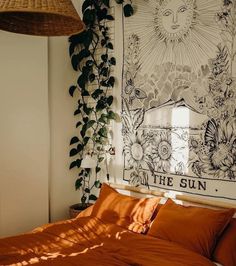 a bed with an orange comforter in front of a sun poster