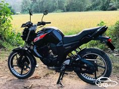 a black motorcycle parked on top of a dirt road