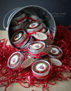 tins filled with red ribbon and labels sitting on a wooden table