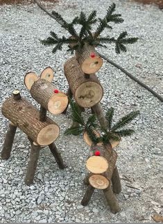 three wooden logs with christmas decorations on them sitting in the middle of a gravel area