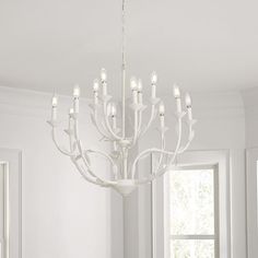 a white chandelier hanging from the ceiling in a room with windows and furniture