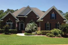 a large brick house with black shutters on the front and side windows is shown