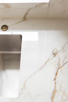 a white marble counter top with a stainless steel faucet in the middle and a square shaped sink below it