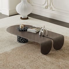 a modern coffee table in the middle of a living room with a vase on top