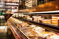 an assortment of cheeses and other food items on display in a store or restaurant