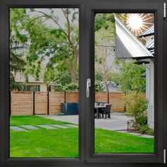 an open sliding glass door in front of a backyard with a table and chairs on the grass