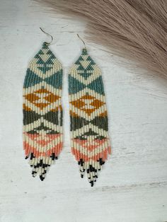 two pairs of beaded earrings on top of a white table next to some hair