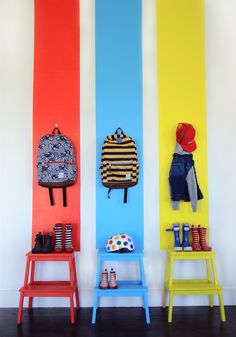 three colorful chairs sitting next to each other in front of a wall with pictures on it