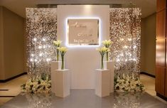 an entrance to a wedding with flowers and lights on the wall behind it is decorated with white tulips