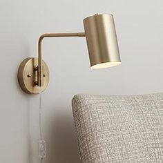 a wall light that is on the side of a bed with a pillow and headboard