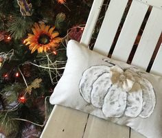 a white chair sitting next to a christmas tree with a pillow on top of it