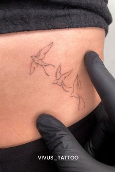 a person with a tattoo on their stomach holding up the side of her body and pointing at it