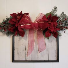 a christmas wreath with poinsettis and greenery hangs on the wall in front of a frame