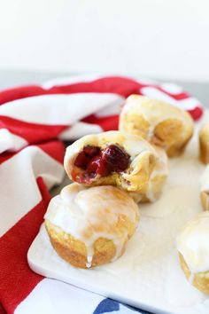 small pastries with icing and strawberries are on a white plate next to an american flag napkin