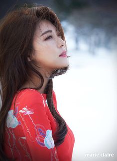 a woman with long brown hair wearing a red shirt and looking up at the sky