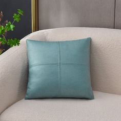 a blue pillow sitting on top of a white couch next to a potted plant