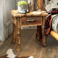 a wooden table with a potted plant on top of it next to a bed