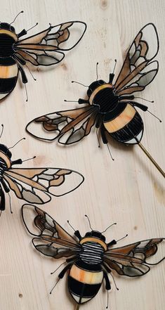 three metal bees sitting on top of a wooden table