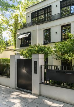 a white building with black doors on the outside and trees in front of it,