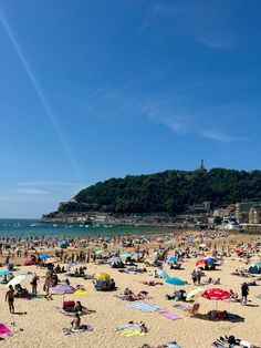 many people are on the beach with umbrellas and towels in the sand near the water