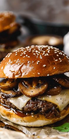 a cheeseburger with mushrooms and onions is on the table next to other burgers