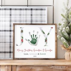 a christmas card with a handprint on it and a pine tree in the background