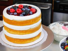 there is a cake with berries on top and other desserts in bowls around it