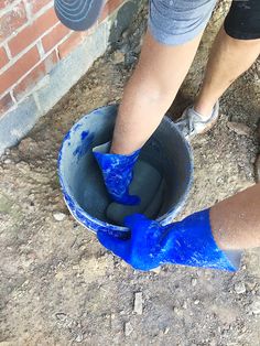 a person in blue rubber boots is holding a bucket