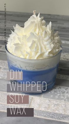 a blue bowl filled with whipped cream sitting on top of a table next to a white wall