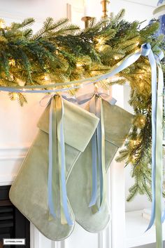 two stockings hanging from a christmas tree with blue ribbon and lights in the background,