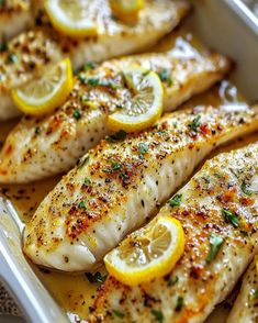 fish with lemon slices and herbs in a white dish