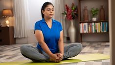 a woman is sitting in the middle of a yoga pose with her eyes closed and hands clasped