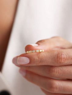 a woman's hand holding a gold ring with three small diamonds on top of it