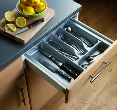 an open drawer in a kitchen with utensils and lemons