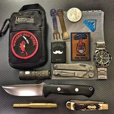 an assortment of knives and other items laid out on a table next to a wallet