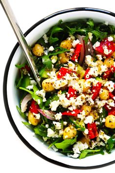 a white bowl filled with salad and topped with feta cheese