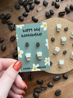 a person holding up a card with small cupcakes on it next to coffee beans