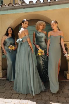 four bridesmaids standing in front of a building