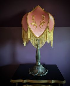 a lamp that is sitting on top of a table in front of a purple wall