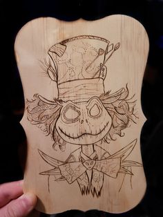 a person holding up a wooden plaque with a drawing on it