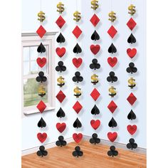 a room decorated with red and black playing cards hanging from the wall, in front of a window