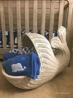 a white wicker baby crib with blue and white blankets in it's back