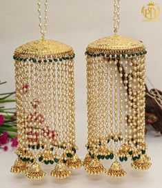 two golden bells with green beads hanging from the sides and on top of each other