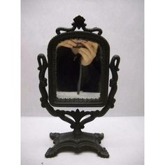 an old fashioned black mirror with a hand holding a candle in it's reflection